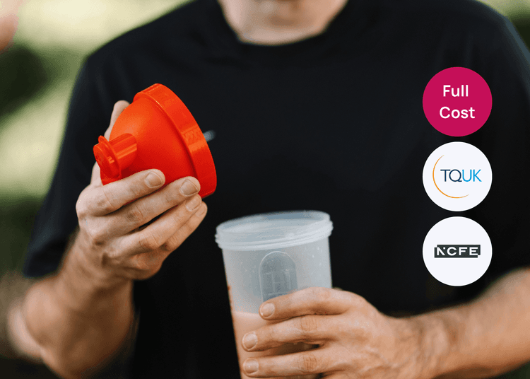 Person holding an orange shaker lid and a protein shaker cup, preparing a drink for nutrition training.