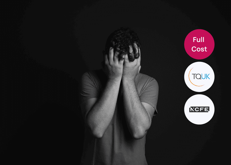 Man standing against a dark background with his hands covering his face, suitable for a mental health awareness course.