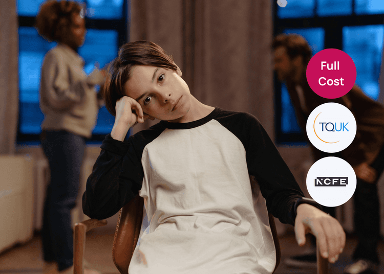 Young person sitting in a chair with their head resting on their hand while two adults talk in the background.