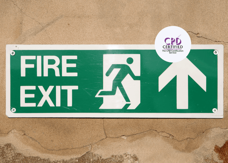 Green fire exit sign on a brown cracked wall with an arrow pointing in the exit direction for fire safety. 