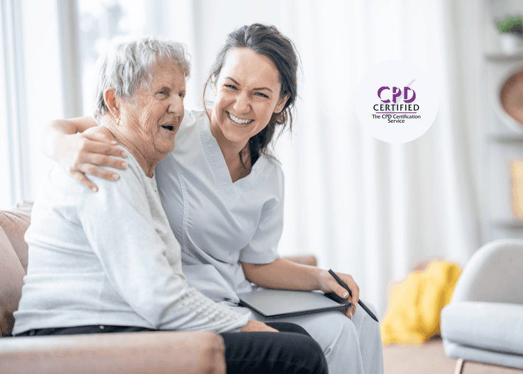 Smiling care worker sits on a sofa with an older woman, both laughing with arms around each other.