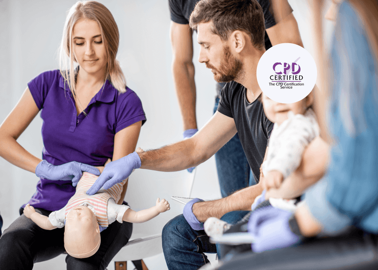 Woman holding infant manikin while man demonstrates first aid technique wearing purple gloves.