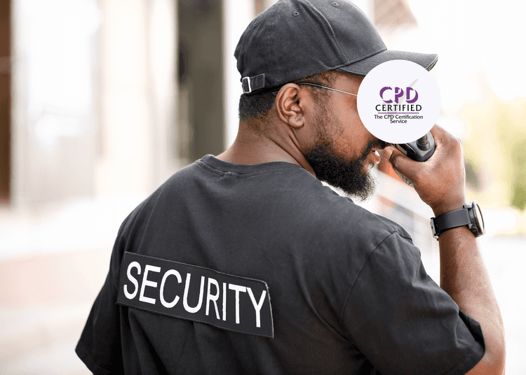 Man in a black cap and t-shirt marked "SECURITY" speaking into a handheld radio outdoors.