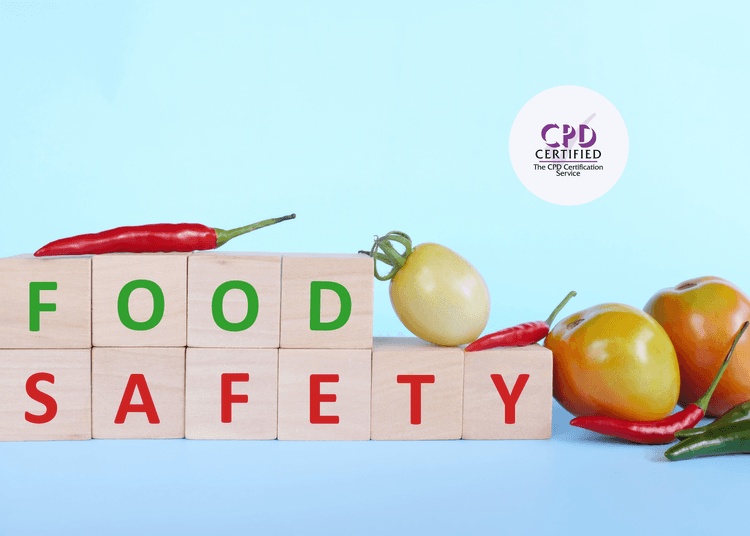 Wooden blocks spelling “FOOD SAFETY” with chillies and tomatoes arranged around them on a light blue background.