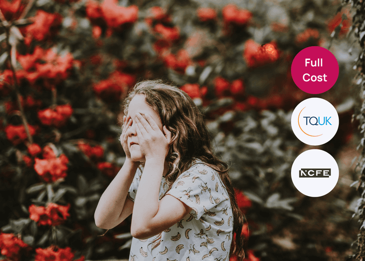 Child covering their face with both hands while standing outdoors among red flowers, linked to adverse childhood experiences.