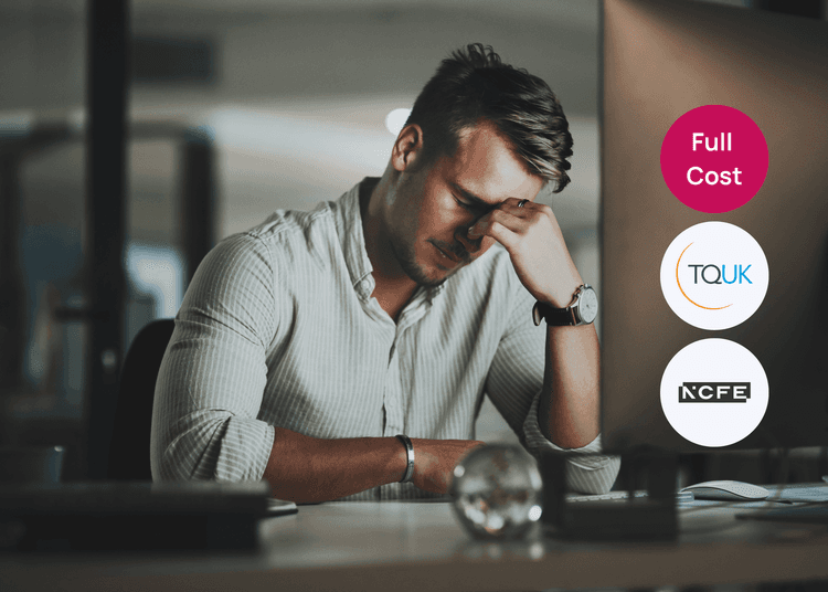 Man sitting at a desk with his hand on his face looking stressed beside a computer, linked to behaviour that challenges.