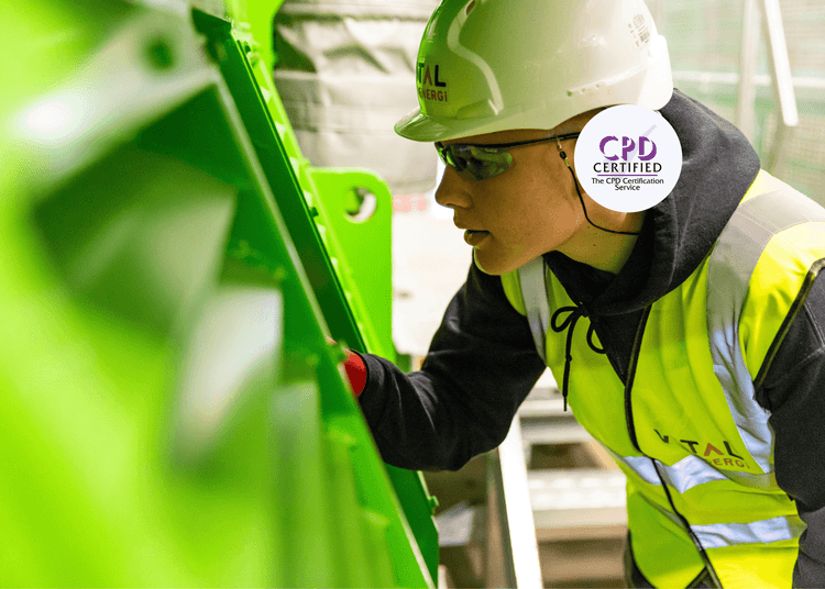 Engineer wearing PPE inspecting industrial machinery in a manufacturing facility.