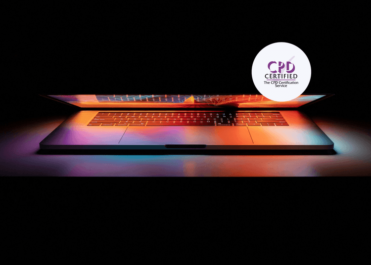 Partially closed laptop glowing with colourful light patterns across the keyboard and screen in a dark room.