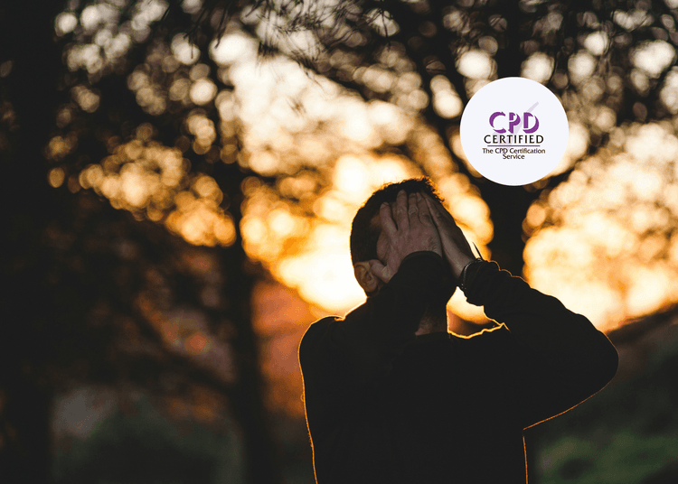 Stressed man standing outdoors at sunset with hands covering his face, surrounded by blurred trees in the background.