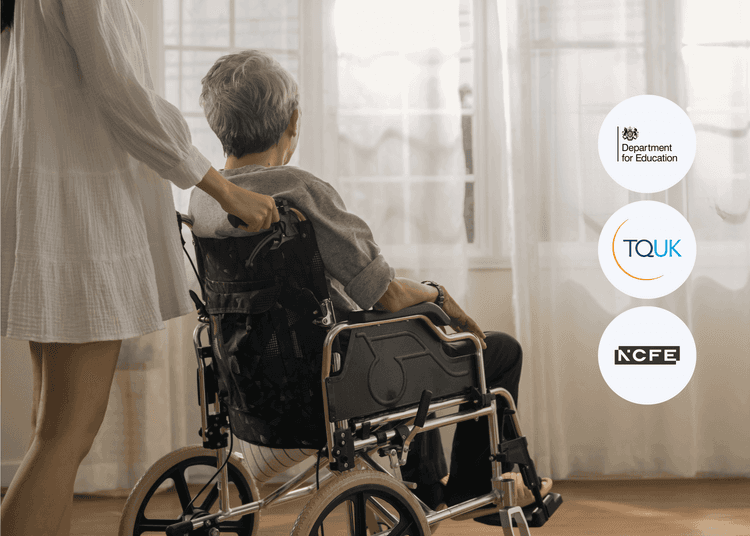 Older person in a wheelchair facing a bright window, being gently pushed by a caregiver in a white dress.