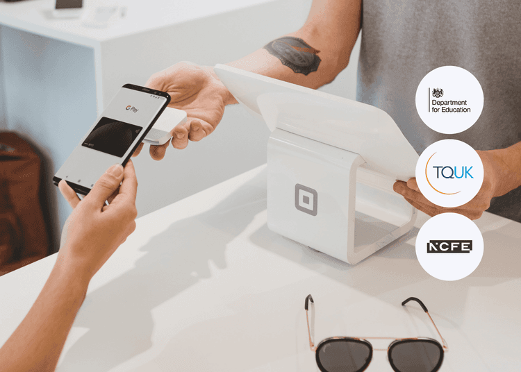 Customer using a smartphone to make a contactless payment at a white card reader held by a retail assistant.