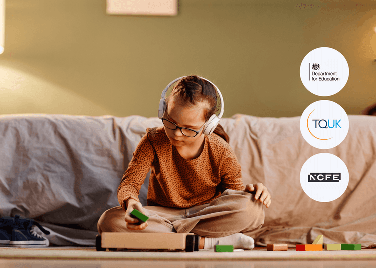 Young girl wearing headphones and glasses sits cross-legged on the floor, focused on placing colourful blocks into a tray.
