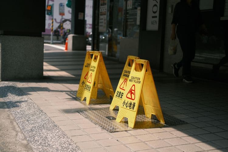 Yellow wet floor signs on a tiled walkway highlight slip hazards linked to Spill Management Training.