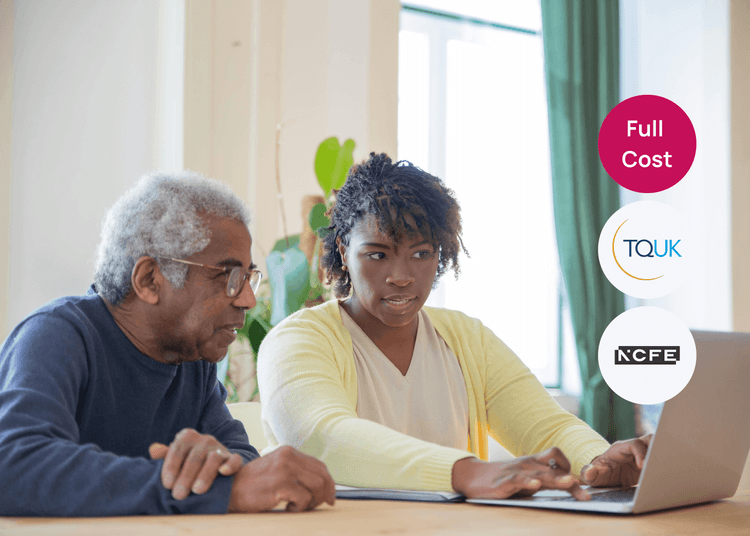 Carer supporting an older person with a laptop task, showing clear and patient customer service in care. Carer sitting beside an older man, helping him use a laptop while discussing something on screen.