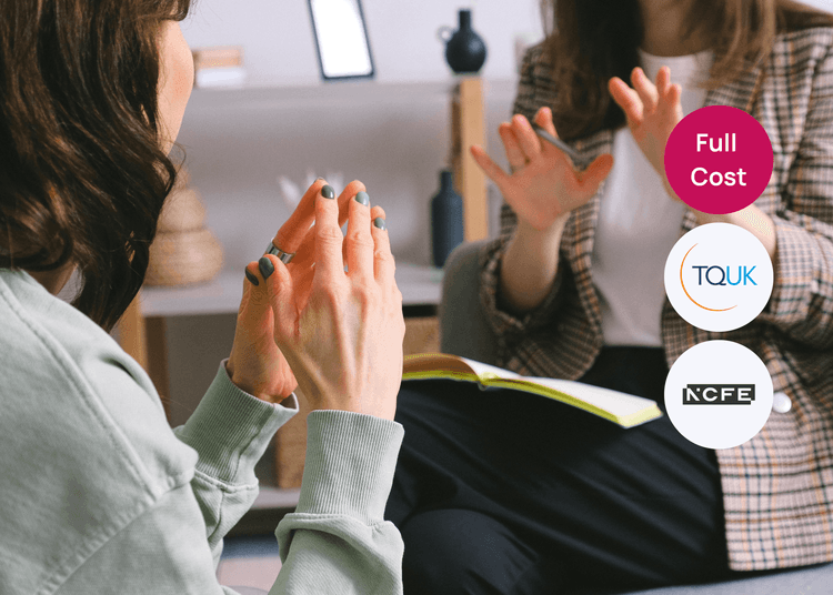 A counselling session in progress with two people communicating through gestures and discussion. Two people sitting and using hand gestures while discussing, with an open notebook visible, relating to counselling training.