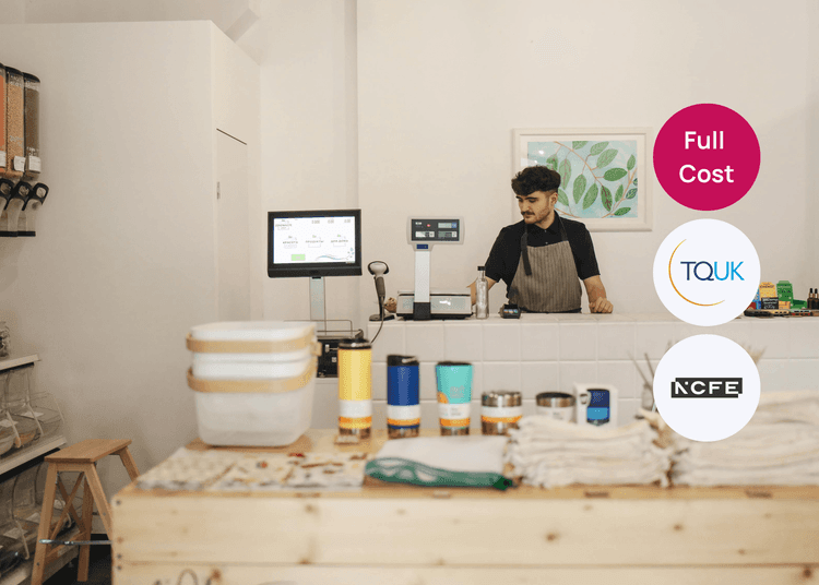 Shop counter with weighing equipment and reusable items to support retail training and customer service learning. Shop worker behind a counter with scales, a monitor, and reusable containers, suitable for a retail skills course.