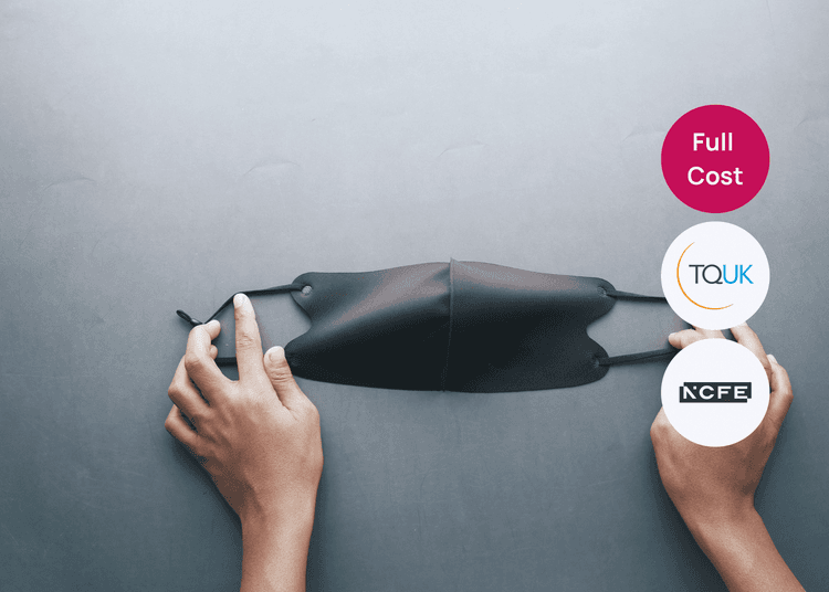 A black face mask held open, highlighting safe practice in infection control and workplace health awareness. Hands holding a black face mask on a grey surface, suitable for a health and safety or infection control course.