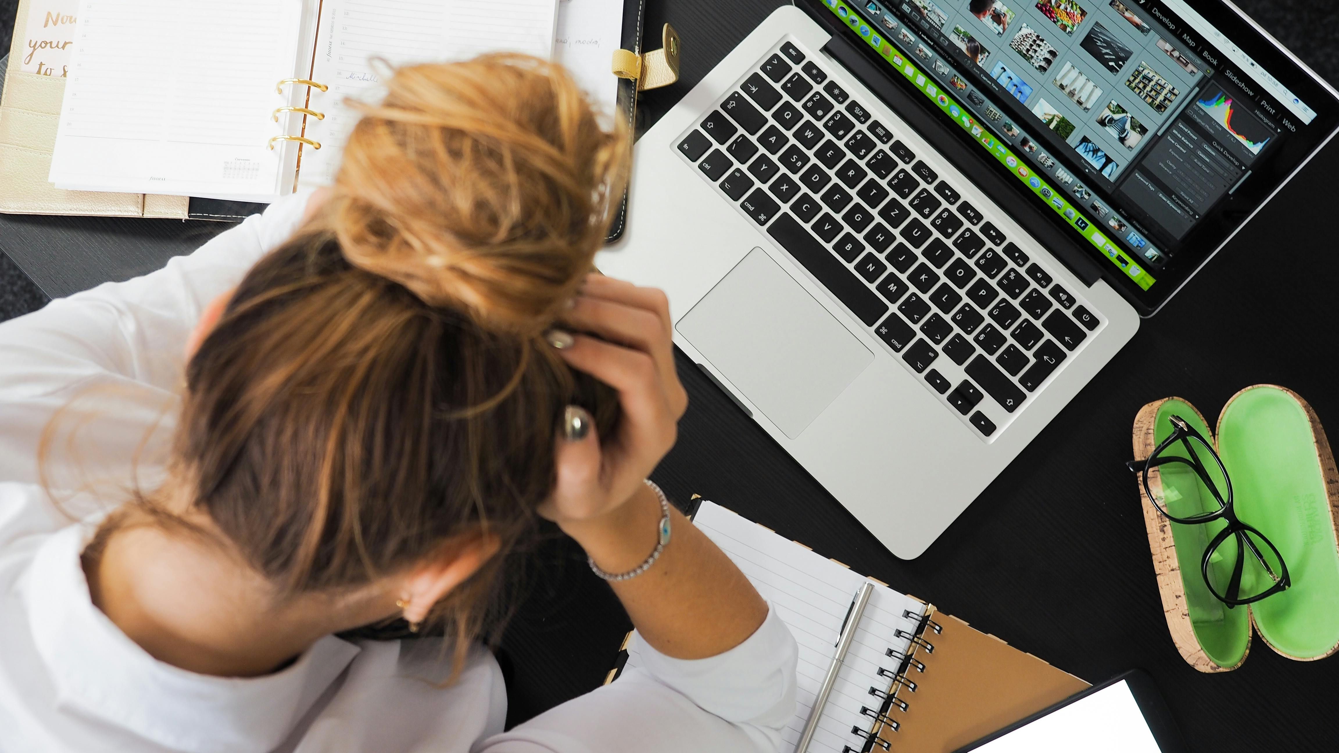 Woman holds her head in her hands due to stress at work